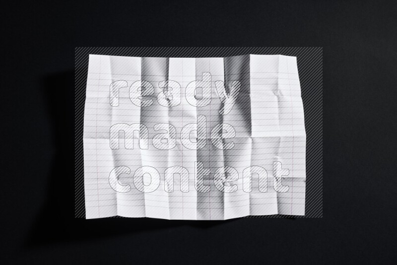 Folded notebook sheet on black background