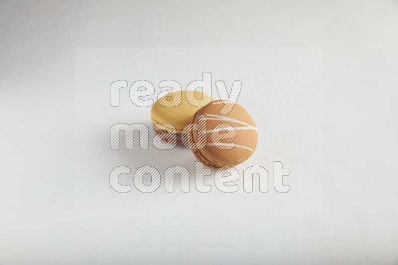 45º Shot of of two assorted Brown Irish Cream, and Yellow, and Brown Chai Latte macarons on white background
