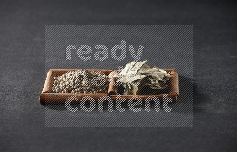 2 squares of cinnamon sticks full of white peppers and bay laurel leaves on black flooring