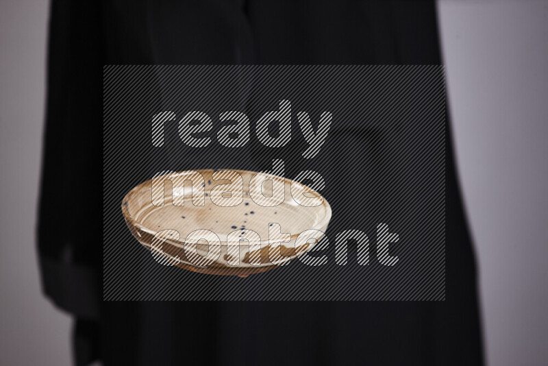 A woman in black abaya holding different pottery essentials in different positions
