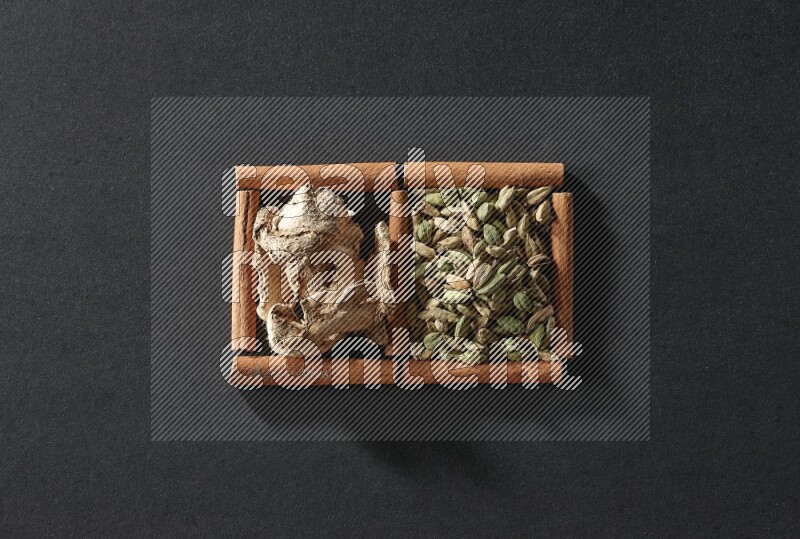 2 squares of cinnamon sticks full of cardamom and dried ginger on black flooring