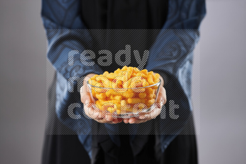 Woman in abaya holding different kinds of snacks in different positions