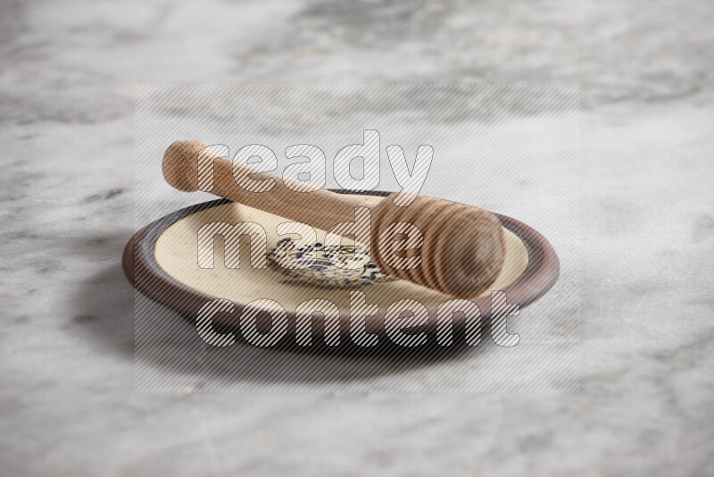 Decorative pottery plate with wooden honey dipper in it on grey marble background