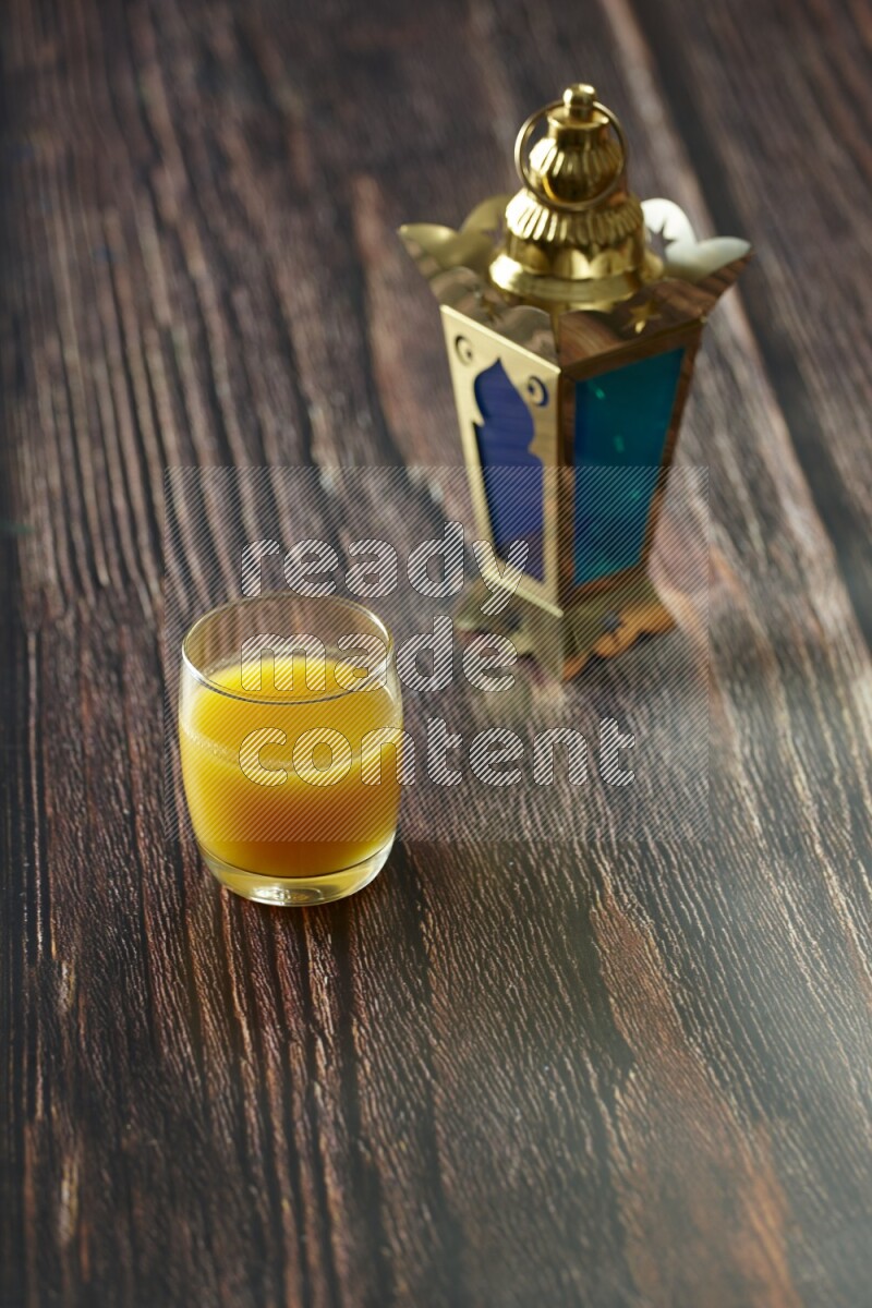 A golden lantern with different drinks, dates, nuts, prayer beads and quran on brown wooden background