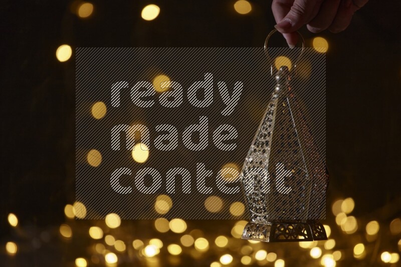 A traditional ramadan lantern surrounded by glowing fairy lights in a dark setup
