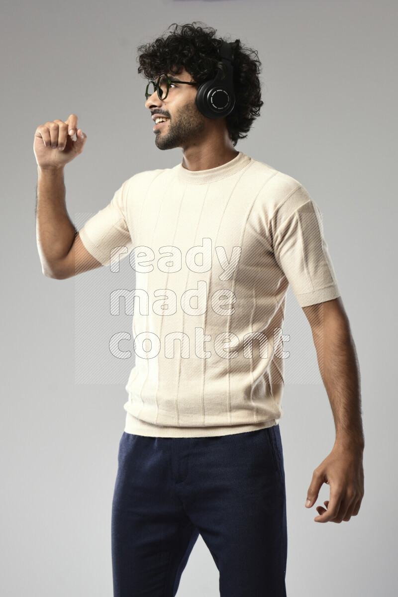 A man wearing casual standing and putting on headphones on white background