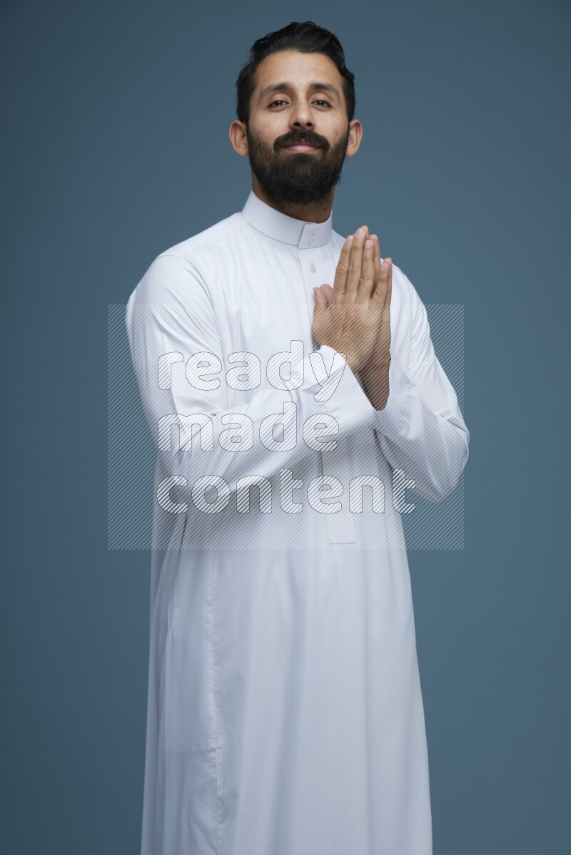 A man posing in a blue background wearing Saudi Thob