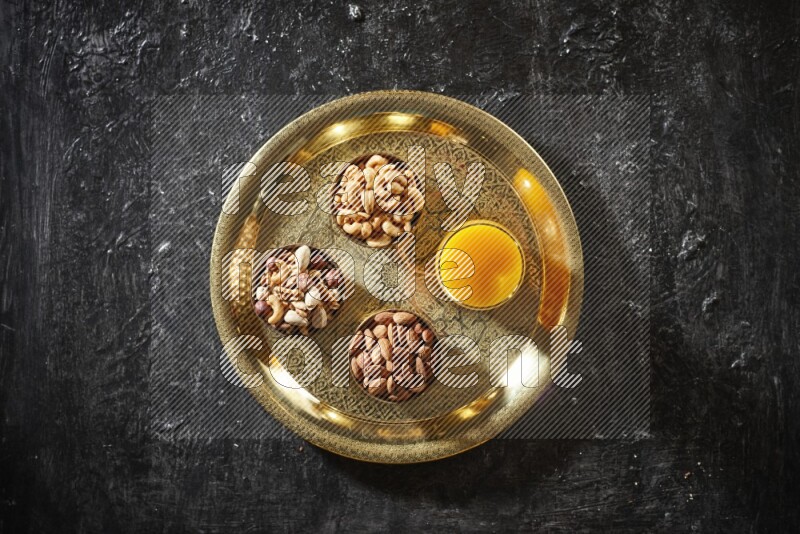 Nuts in metal bowls with qamar eldin on a tray in dark setup