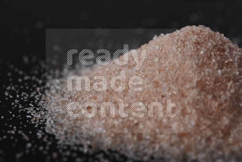 A bunch of fine himalayan pink salt on black background
