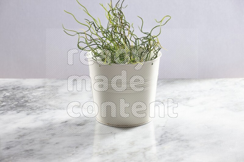 Green artificial plant in white pot on light grey marble background