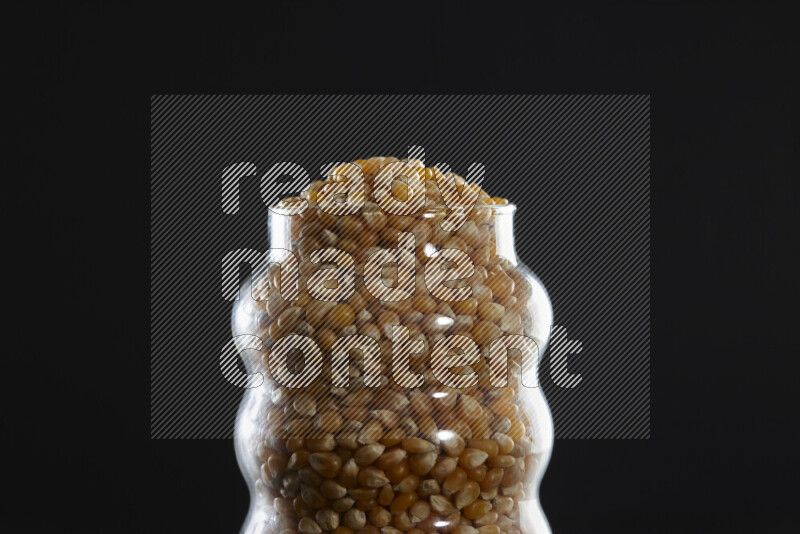 Pop corn in a glass jar on black background
