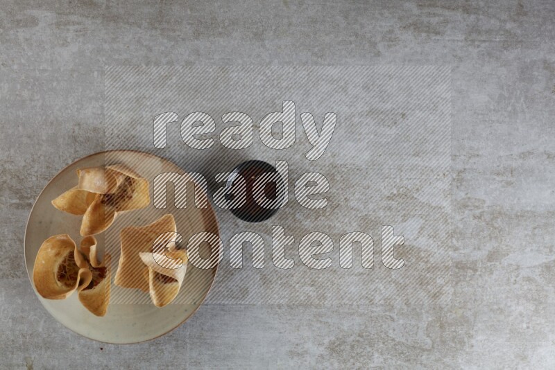 wonton cups with soy sauce ramkin on multi colored pottery on grey textured counter top