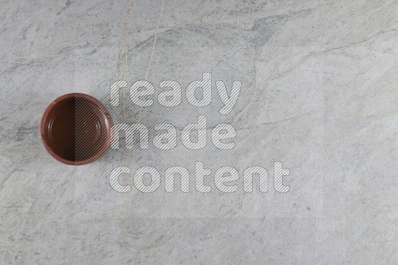 A brown pottery bowl on grey marble background