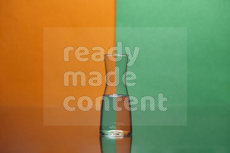 The image features a clear glassware filled with water, set against orange and green background
