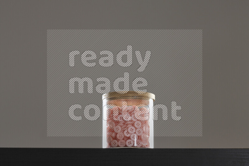 أزرار متنوعة في وعاء زجاجي علي خلفية سوداء