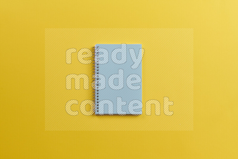 A blue notebook with different school supplies on yellow background