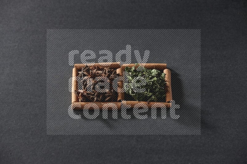 مربعان من أعواد القرفة ممتلئان باليانسون النجمي والنعناع المجفف علي خلفية سوداء