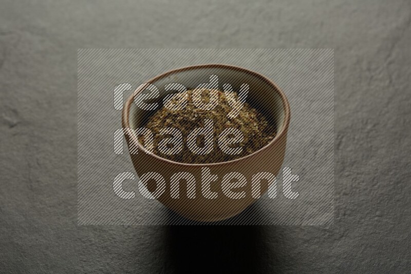 multi color round sauce bowl filled with herbs on grey textured countertop