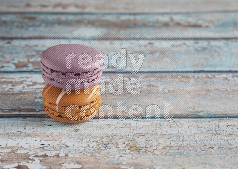 45º Shot of of two assorted Brown Irish Cream, and Purple Blueberry macarons  on light blue background