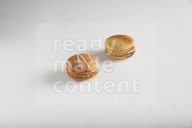 45º Shot of of two assorted Brown Irish Cream, and Yellow Crème Brulée macarons on white background