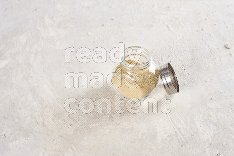 A glass jar full of ground ginger powder on white background