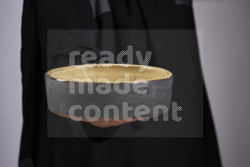 امرأة ترتدي عباءة سوداء تحمل أدوات فخارية مختلفة في أوضاع متعددة