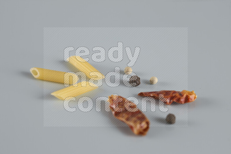 Raw pasta with different ingredients such as cherry tomatoes, garlic, onions, red chilis, black pepper, white pepper, bay laurel leaves, rosemary, cardamom and mushrooms on light blue background