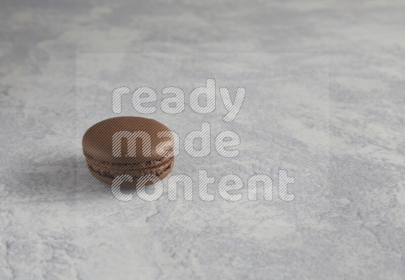 45º Shot of Brown Dark Chocolate macaron on white  marble background