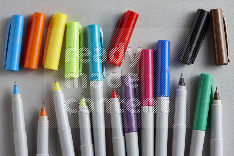 An arrangement of coloring pens in different colors on grey background