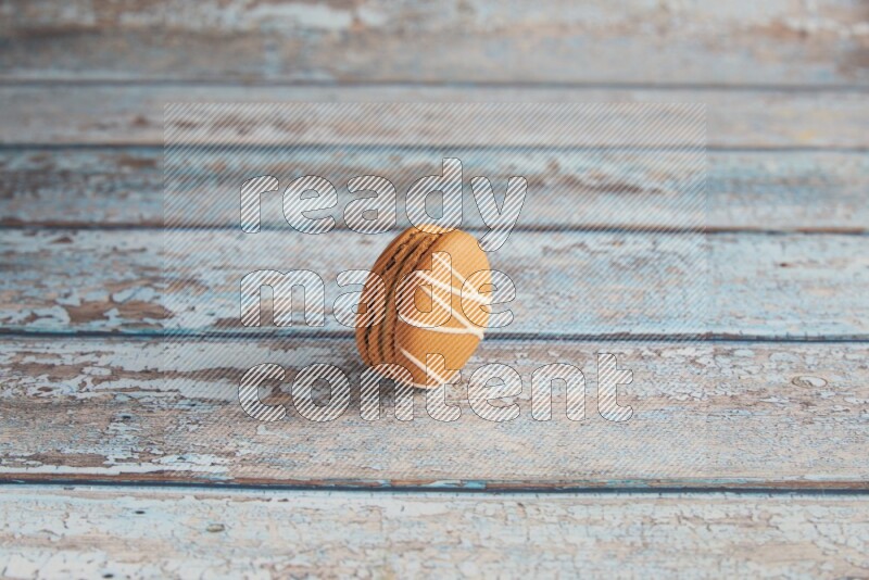 45º Shot of Brown Irish Cream macaron on light blue wooden background