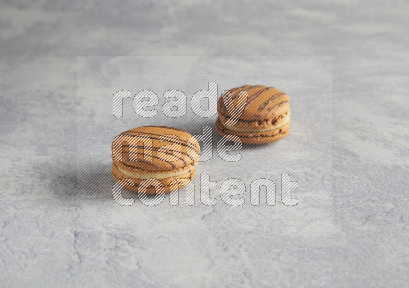 45º Shot of two light brown  Almond Cream macarons  on white  marble background