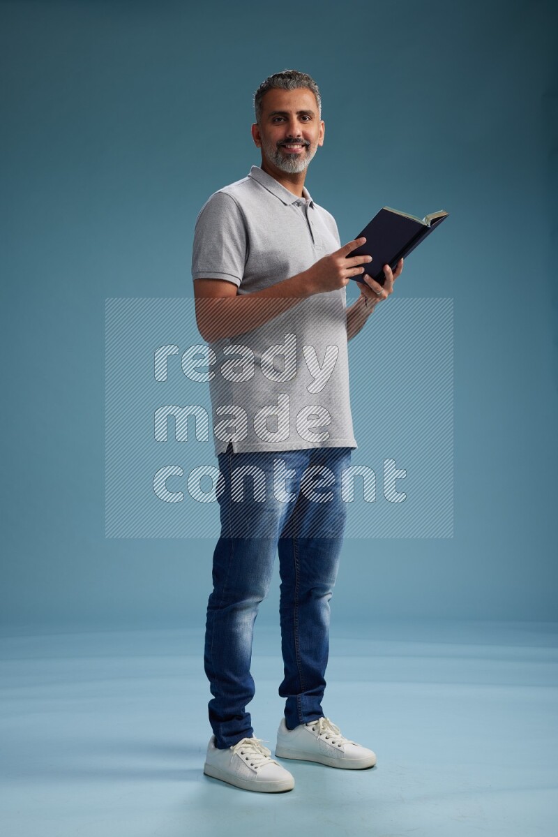 Man Standing reading book on blue background