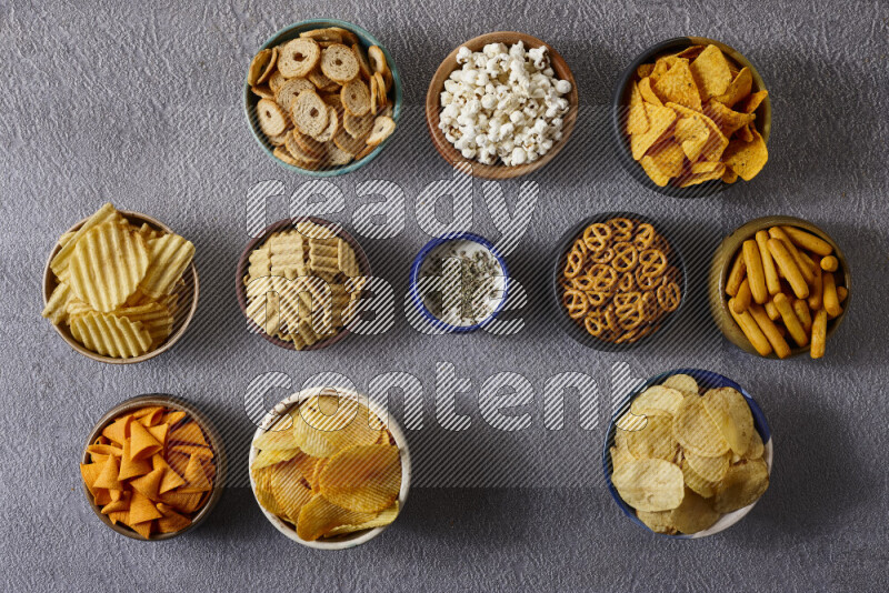 Assorted snacks in pottery bowls on grey background