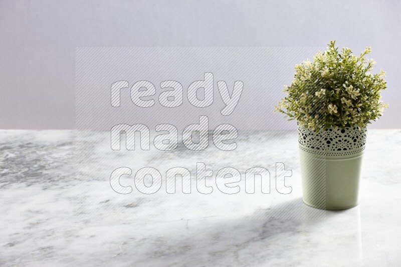 Artificial plant in green decorative pot on grey marble background