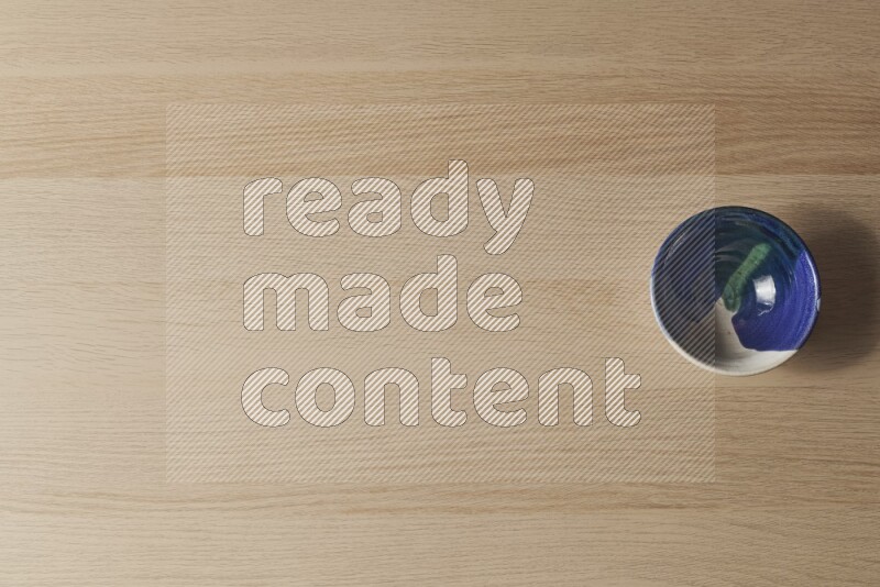 A multicolored pottery bowl on light wooden background