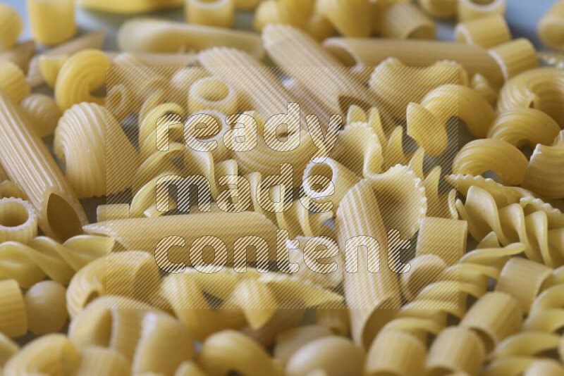 Different pasta types on light blue background
