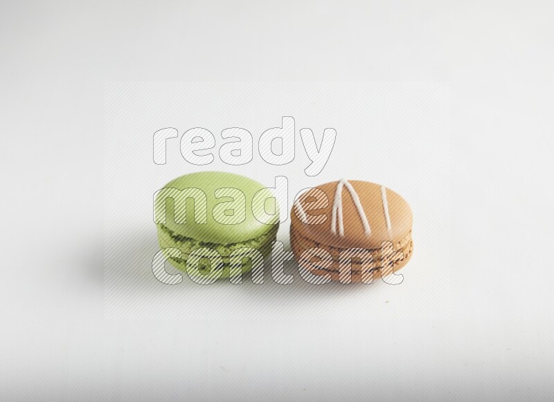 45º Shot of of two assorted Brown Irish Cream, and Green Pistachio macarons on white background