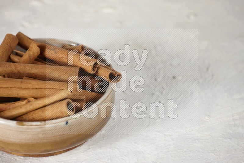Cinnamon sticks in a ceramic bowl in different angles on white background
