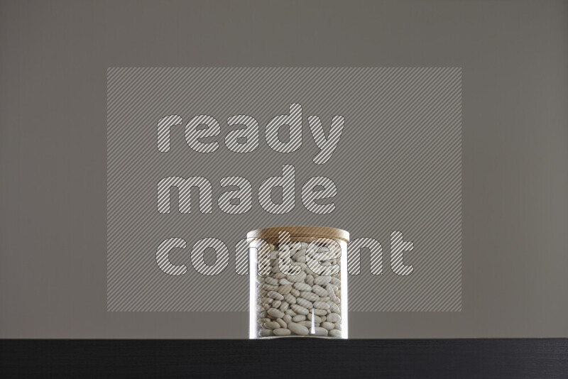 White beans in a glass jar on black background