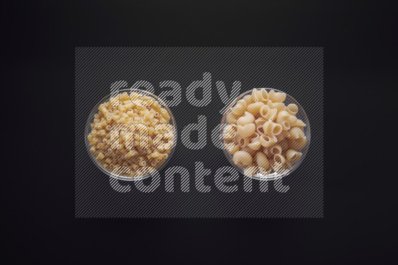 Different pasta types in glass bowls on black background