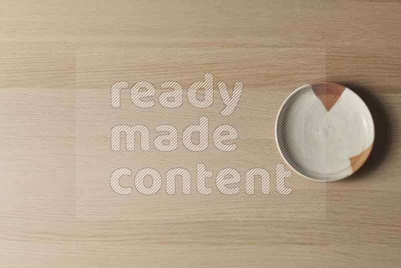 A multicolored pottery plate on light wooden background