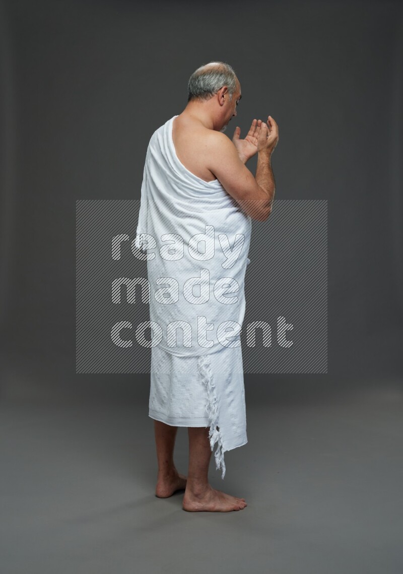 A man wearing Ehram Standing dua'a on gray background