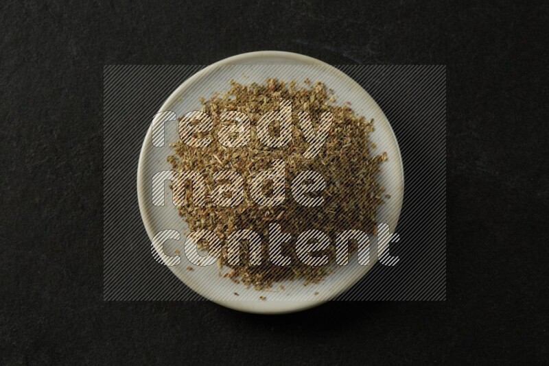 white ceramic round sauce dish filled with herbs on grey textured countertop