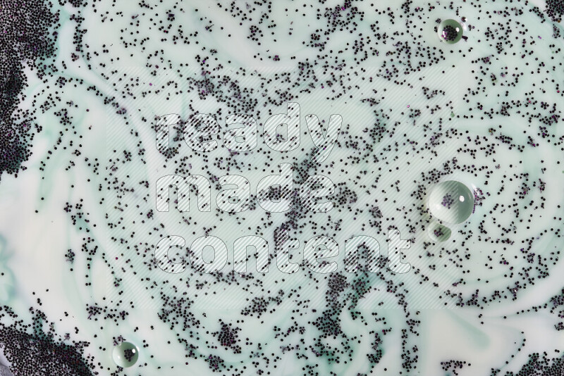 A close-up of sparkling purple glitter scattered on swirling green and white background