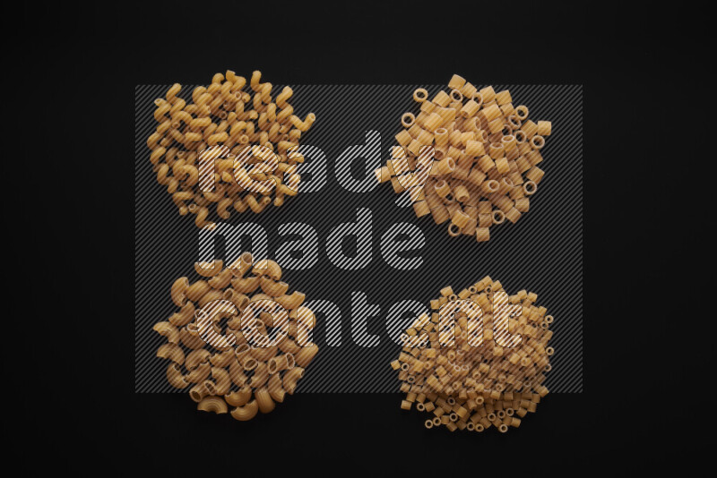 Different pasta types in bunches on black background