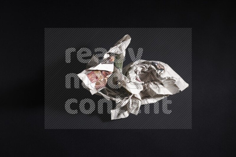 Crumpled newspaper sheet on black background