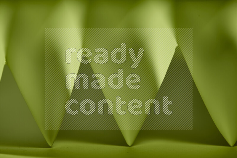 A close-up abstract image showing sharp geometric paper folds in green gradients