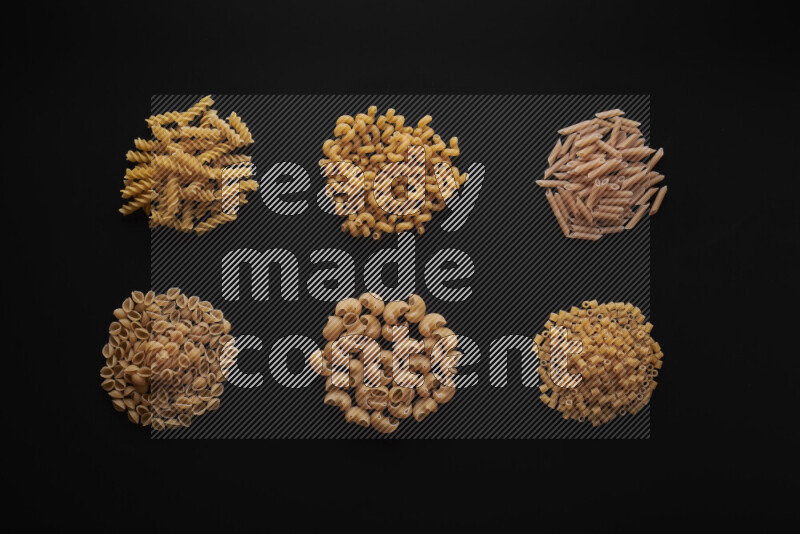 Different pasta types in bunches on black background