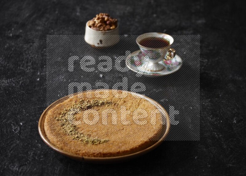 Konafa with nuts and tea in a dark setup
