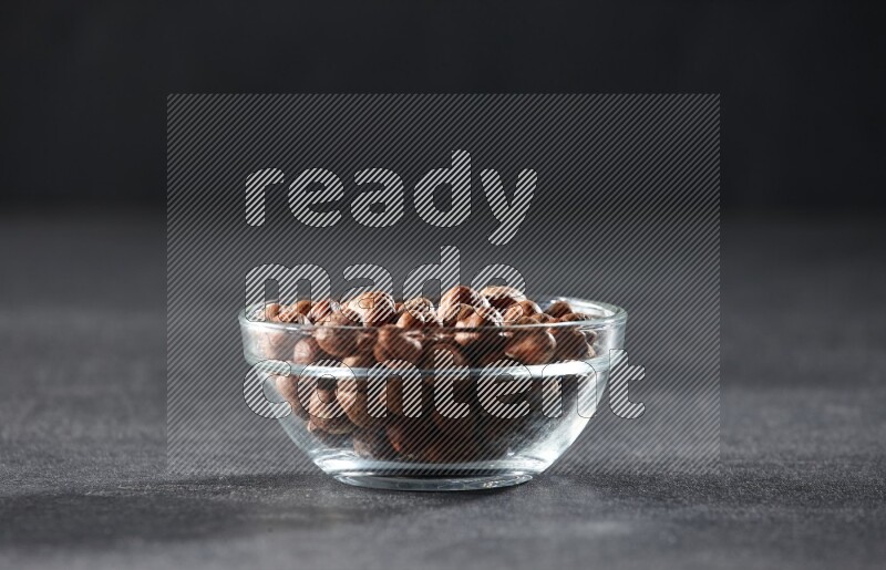 A glass bowl full of peeled hazelnuts on a black background in different angles